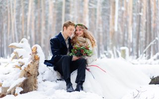 Mariée en robe blanche et étole chaude avec son marié dans une forêt enneigée