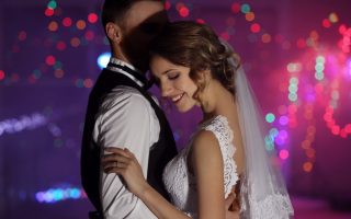 Mariée en robe de dentelle et voile enlaçant son époux pendant la soirée dansante